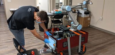 Dean Conte, a master’s student in mechanical engineering, with a robotic decontaminator that he helped to develop.