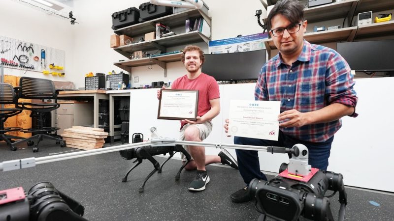 (from left) Randy Fawcett and  Kaveh Akbari Hamed with their awards and robots.