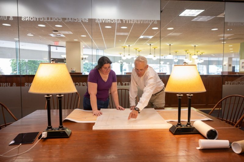 Library staff member and Woodhouse look over mining documents in Special Collections.