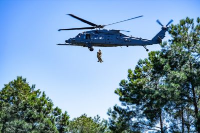 An HH-60W helicopter hoists a pararescuemen during training 