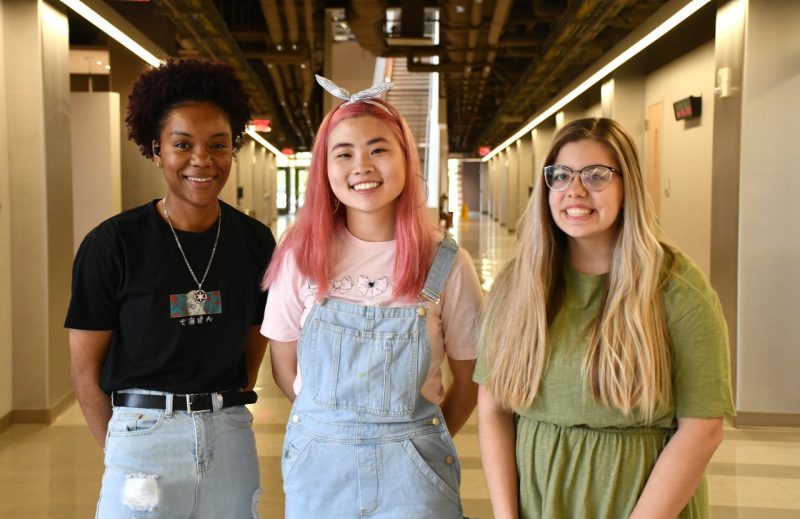 Left to right, Camille Bridgewater, Sera Choi, and Nikki Keith have won scholarships from the Arnold and Mabel Beckman Foundation. In the photo, the trio are standing in the center of the main hallway of the New Classroom Building. All are smiling toward the camera. Photo for Virginia Tech by Steven Mackay. 