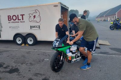 Two team members push the the Bolt motorcycle from their transport trailer.