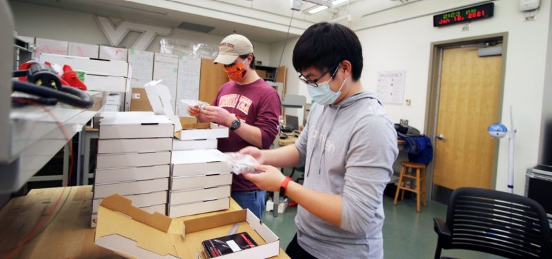 Students Travis Bowman and Henry Zhao help with assembly of take-home lab kits.